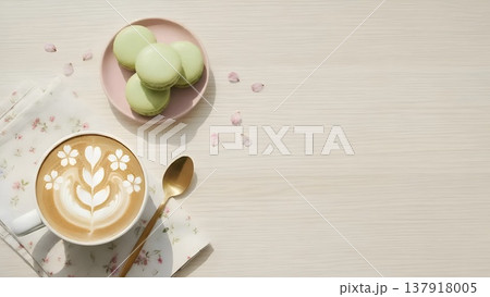 桜のラテアートのコーヒーと抹茶マカロンを木目の背景に並べ、桜の花びらを添えたフラットレイ 137918005