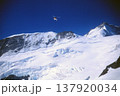 夏のスイスアルプス　雪山の上を飛ぶヘリコプター 137920034