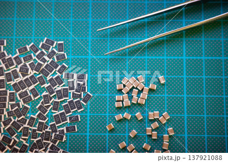 SMD resistors and capacitors with tweezers on cutting mat, electronics assembly concept 137921088