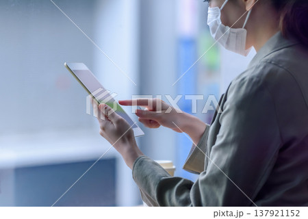 タブレットを操作するマスク姿の女性 137921152