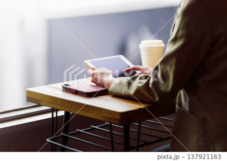 カフェでタブレットを操作する女性の手元 137921163