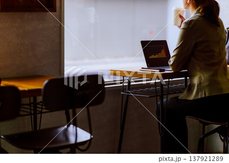 窓際のカフェでコーヒーを片手にPCを見る女性 窓際のカフェでコーヒーを片手にPCを見る女性 137921289