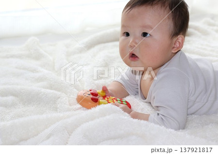うつ伏せでおもちゃで遊ぶ赤ちゃん うつ伏せでおもちゃで遊ぶ赤ちゃん 137921817