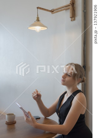 Casual young business woman using digital tablet while sitting at table in cafe Casual young business woman using digital tablet while sitting at table in cafe 137921906