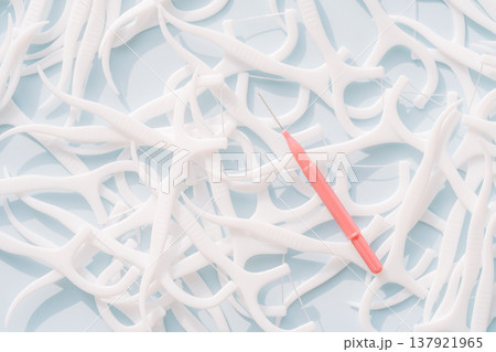 Interdental brush on background of many floss picks, dental cleaning tools comparison concept 137921965