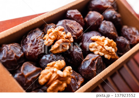 A close-up of two plates containing dates and walnuts, accompanied by cinnamon sticks prepared for Iftar at Ramadan. The scene highlights healthy snacks and natural ingredients. 137923552