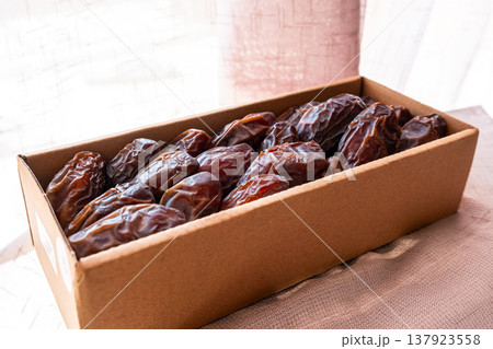 A close-up of two plates containing dates and walnuts, accompanied by cinnamon sticks prepared for Iftar at Ramadan. The scene highlights healthy snacks and natural ingredients. 137923558