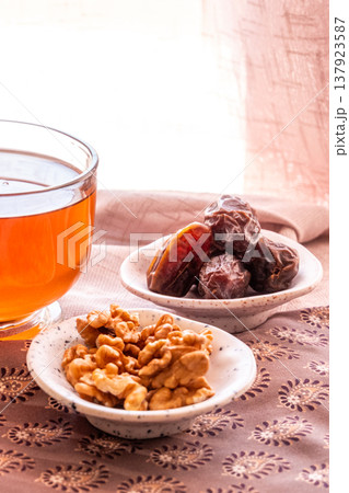 A close-up of two plates containing dates and walnuts, accompanied by cinnamon sticks prepared for Iftar at Ramadan. The scene highlights healthy snacks and natural ingredients. A close-up of two plates containing dates and walnuts, accompanied by cinnamon sticks prepared for Iftar at Ramadan. The scene highlights healthy snacks and natural ingredients. 137923587
