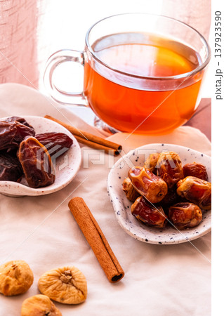 A close-up of two plates containing dates and walnuts, accompanied by cinnamon sticks prepared for Iftar at Ramadan. The scene highlights healthy snacks and natural ingredients. 137923590