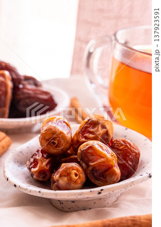 A close-up of two plates containing dates and walnuts, accompanied by cinnamon sticks prepared for Iftar at Ramadan. The scene highlights healthy snacks and natural ingredients. A close-up of two plates containing dates and walnuts, accompanied by cinnamon sticks prepared for Iftar at Ramadan. The scene highlights healthy snacks and natural ingredients. 137923591