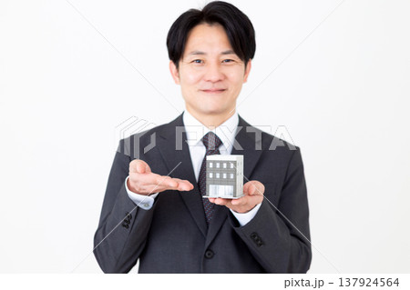 企業ビルの住宅模型を持つミドル男性ビジネスマン 137924564
