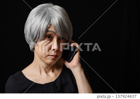 虚ろな表情でスマホで通話する白髪のシニア女性 虚ろな表情でスマホで通話する白髪のシニア女性 137924637