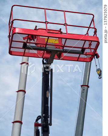 Working platform is raised high in the sky during construction project above a building under clear blue sky Working platform is raised high in the sky during construction project above a building under clear blue sky 137925079
