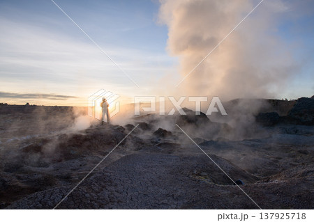 Awe inspiring sunrise at Sol de Manana geyser with steam and person Awe inspiring sunrise at Sol de Manana geyser with steam and person 137925718