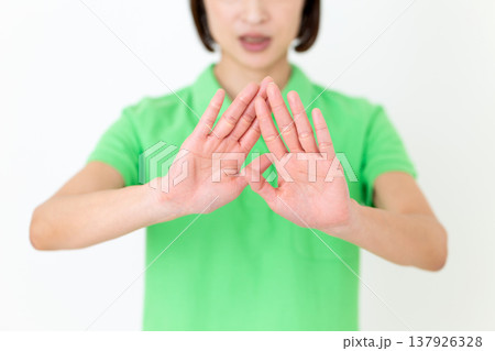 両手を前に出して拒否するミドル女性の介護福祉士 両手を前に出して拒否するミドル女性の介護福祉士 137926328