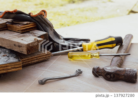 Working tools, wood, protective gloves on a table outdoors, celebrating labor day Working tools, wood, protective gloves on a table outdoors, celebrating labor day 137927280