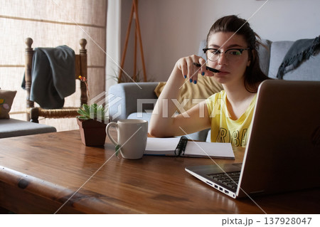 Teenager looking at computer in study session at home Teenager looking at computer in study session at home 137928047
