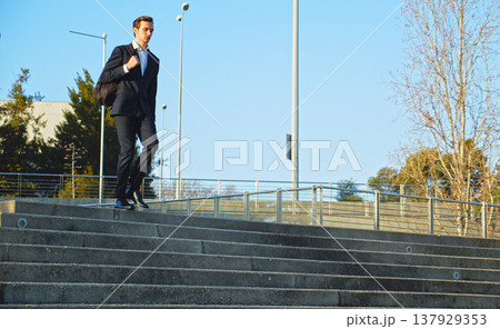 Young Businessman in black classic shoes and trousers going down the steps. Young handsome man in fashionable black suit with a backpack walking down the steps. 137929353