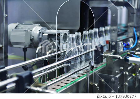 Conveyor belt with empty glass bottles in a modern bottling factory line 137930277