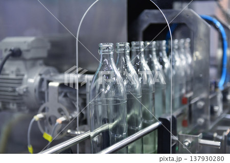 Conveyor belt with empty glass bottles in a modern bottling factory line 137930280