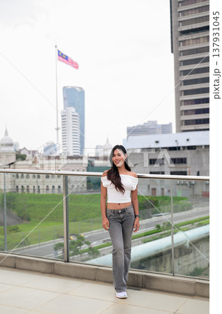 Portrait of woman against Kuala Lumpur city skyline with National Textile Museum and Malaysian flag 137931045