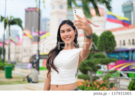 Thai Woman at Merdeka Square Kuala Lumpur using phone in front of the Sultan Abdul Samad Building. Thai Woman at Merdeka Square Kuala Lumpur using phone in front of the Sultan Abdul Samad Building. 137931065
