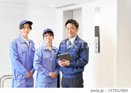 エレベーターホールでタブレットを持つ設備管理リーダーと若手作業員の男女 137932900