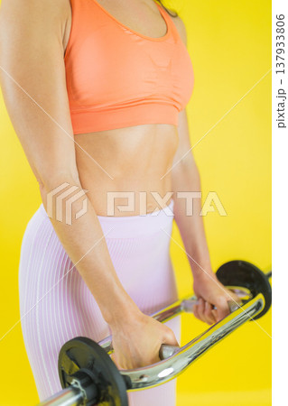 Woman exercising biceps with curling bar for fitness 137933806