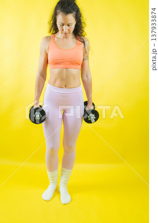 Woman holding dumbbells preparing for strength training Woman holding dumbbells preparing for strength training 137933874