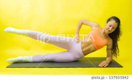 Woman performing side leg raise exercise on exercise mat 137933942