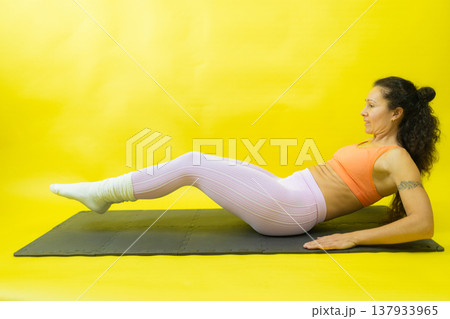 Woman exercising core muscles on yellow background 137933965