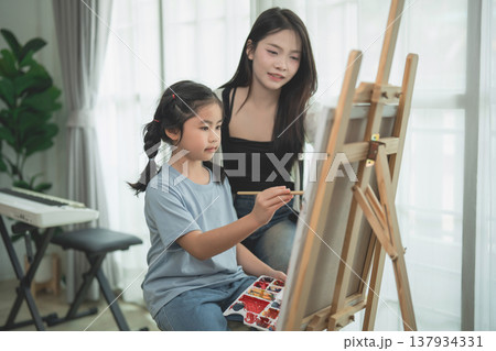 Young girl painting with mother in cozy indoor setting, nurturing creativity and artistic skills in a bright and inspiring atmosphere Young girl painting with mother in cozy indoor setting, nurturing creativity and artistic skills in a bright and inspiring atmosphere 137934331