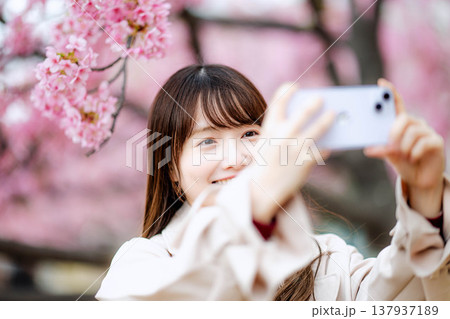 桜と撮影する女性 137937189