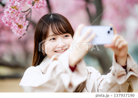 桜と撮影する女性 137937190