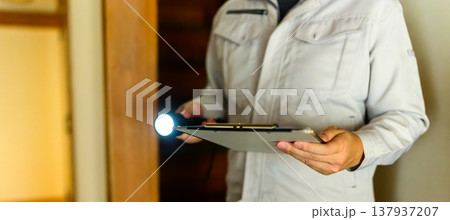 作業着の男性が懐中電灯と書類を持つ 137937207