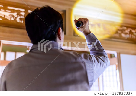 懐中電灯で和室の天井を照らす男性 137937337