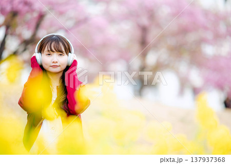 桜の中でヘッドホンで音楽を聴く若い女性 137937368
