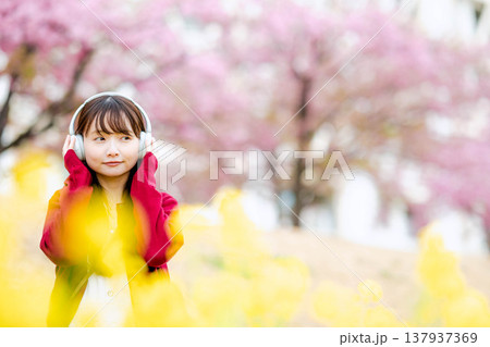 桜の中でヘッドホンで音楽を聴く若い女性 桜の中でヘッドホンで音楽を聴く若い女性 137937369
