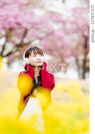 桜の中でヘッドホンで音楽を聴く若い女性 137937372