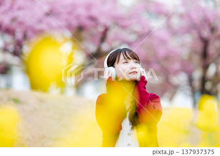 桜の中でヘッドホンで音楽を聴く若い女性 桜の中でヘッドホンで音楽を聴く若い女性 137937375