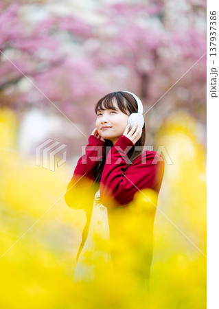 桜の中でヘッドホンで音楽を聴く若い女性 桜の中でヘッドホンで音楽を聴く若い女性 137937386