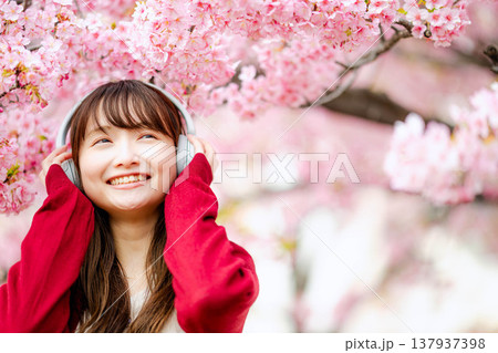 桜の中でヘッドホンで音楽を聴く若い女性 桜の中でヘッドホンで音楽を聴く若い女性 137937398