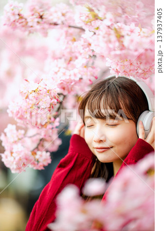 桜の中でヘッドホンで音楽を聴く若い女性 桜の中でヘッドホンで音楽を聴く若い女性 137937405