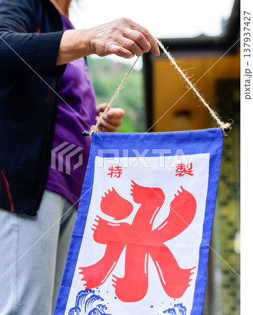 屋外でかき氷の特製旗を準備する女性の手元 137937427