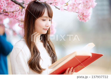 桜の木の前で読書をする若い女性 桜の木の前で読書をする若い女性 137937722