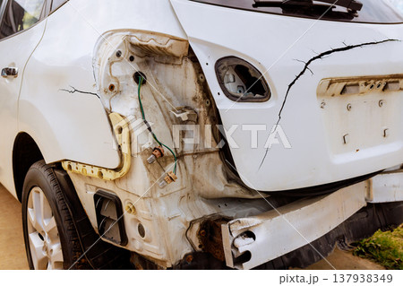 Damaged car is parked on street cracked rear end with exposed wires parts Damaged car is parked on street cracked rear end with exposed wires parts 137938349