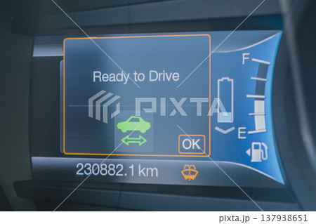 Close-up of a modern digital car dashboard ready for travel. The illuminated instrument cluster shows a zero speedometer, full fuel level, and clear safety status 137938651