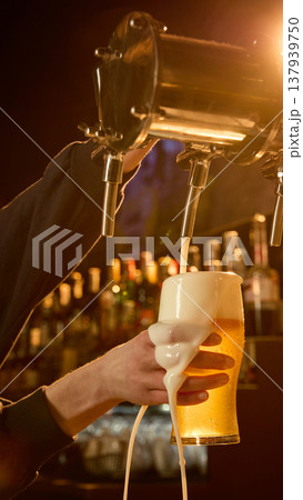 Beer tap system close up with bartender pouring draft beer under warm light. Beer tap system close up with bartender pouring draft beer under warm light. 137939750
