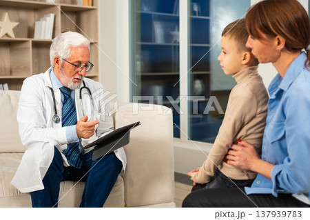 Visit to pediatrician doctor. Mother with little preschooler son visit consult male pediatrician at hospital. Doctor examining boy. Family and doctor have consultation in doctor office clinic at home Visit to pediatrician doctor. Mother with little preschooler son visit consult male pediatrician at hospital. Doctor examining boy. Family and doctor have consultation in doctor office clinic at home 137939783