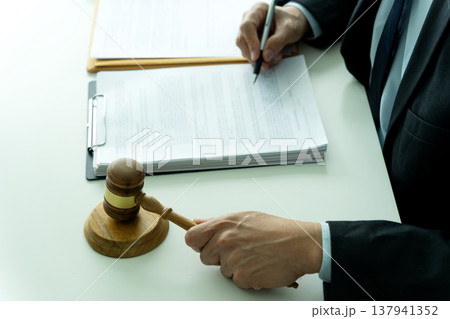 lawyer sitting and holding gavel hands preparing to smash on pedestal symbolizing lawyer sitting and holding gavel hands preparing to smash on pedestal symbolizing 137941352